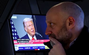 トランプ米大統領のインタビュー放送を見つめるニューヨーク証券取引所のトレーダー(21日)=ロイター