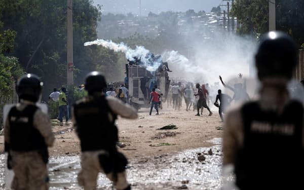 17日、ハイチの首都ポルトープランスで、首相の辞任を求める抗議デモに対し催涙弾を使う警察当局者ら=ロイター