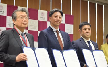 九州大学との連携協定書を手にするPwCジャパングループの久保田正崇代表(中央)ら=30日、福岡市