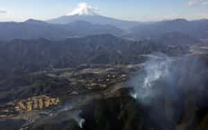 延焼が続く山梨県上野原市の扇山(手前)と富士山。奥は富士山(1月11日)=共同 延焼が続く山梨県上野原市の扇山(手前)と富士山。奥は富士山(1月11日)=共同