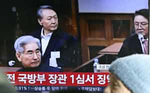 ソウル駅のテレビに映し出された尹錫悦前大統領(奥)の判決公判の映像(19日)=共同 ソウル駅のテレビに映し出された尹錫悦前大統領(奥)の判決公判の映像(19日)=共同