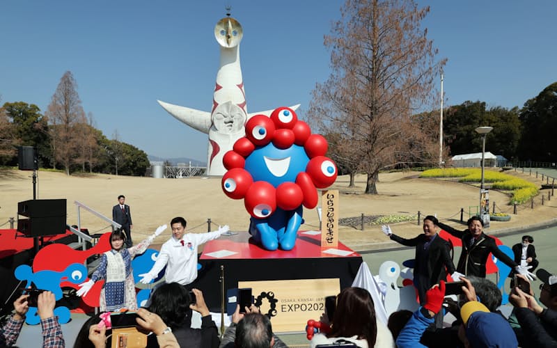 万博記念公園で開かれた「ミャクミャク」像の移設セレモニー。奥は太陽の塔(21日、大阪府吹田市)
