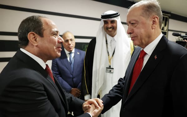 握手するトルコのエルドアン大統領㊨とエジプトのシシ大統領㊧（20日、ドーハ）＝トルコ大統領府・ロイター