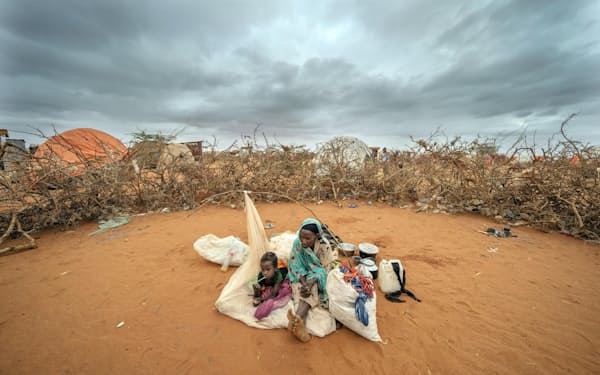 干ばつが長く続くソマリアの避難民キャンプで待機する女性と子ども（9月）＝AP