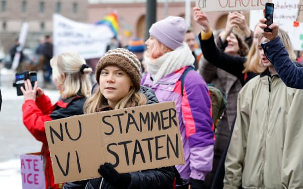 25日、デモで「今から国を提訴する」と書いた段ボールを持つグレタさん＝スウェーデン通信・ＡＰ