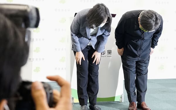 26日、台湾統一地方選で民進党が大敗し、記者会見で頭を下げる蔡英文総統（左）＝共同