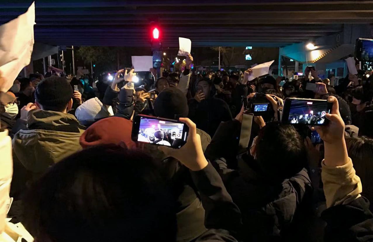 中国の「ゼロコロナ」政策に反対し、当局への抗議を意味する白い紙を掲げる人たち（28日、北京）=共同