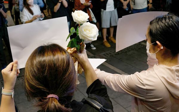 28日、香港で白い紙を掲げて抗議する人々=ロイター
