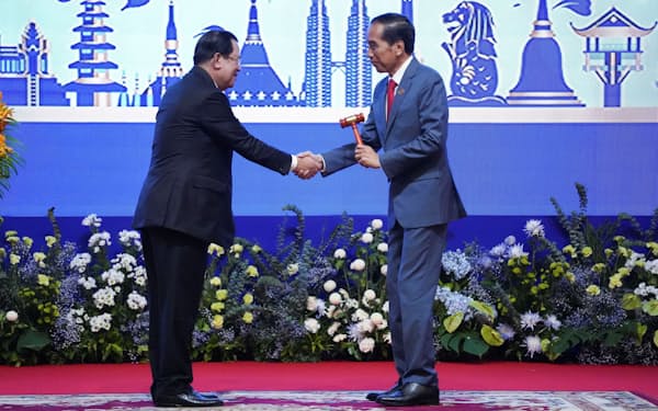 カンボジアのフン・セン首相㊧から、議長国の引き継ぎを受けるインドネシアのジョコ大統領（11月、プノンペン）＝ロイター
