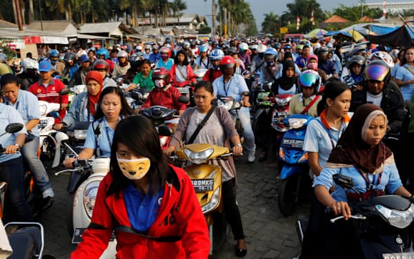 FILE PHOTO: Workers of a shoe factory on their motorcycles are stuck in a traffic jam as they make their home after work, at Pasar Kemis industrial park in Tangerang August 14, 2014. Negotiations over pay and working conditions have typically remained within national borders, but activists are now bringing more muscle to the table and putting more pressure on employers and governments by using shared experiences in nearby markets. Said Iqbal, who heads the Confederation of Indonesian Trade Unions, with more than 1.4 million members, said he has been invited to Malaysia, Vietnam, Cambodia and Laos to share his experiences with other activists. Picture taken August 14. To match story ASIA-LABOUR/ REUTERS/Beawiharta (INDONESIA - Tags: BUSINESS EMPLOYMENT TRANSPORT)/File Photo
