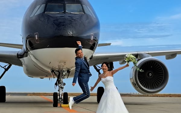 スターフライヤーの機体をバックにポーズをとる松下慎太郎さんと佳菜子さん（9日、北九州空港）