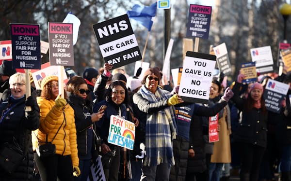 プラカードを掲げてストライキに参加する看護師たち（15日、ロンドン）＝ロイター