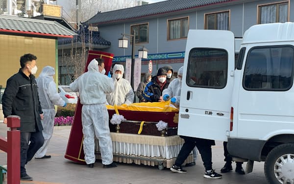 コロナまん延の中、防護服を着て死亡者の遺体を運ぶ作業をする人々（17日、北京）＝ロイター