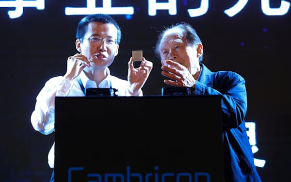 イベントでクラウドサービス向けAI半導体を手にするカンブリコン創業者の陳天石氏（左）=ロイター