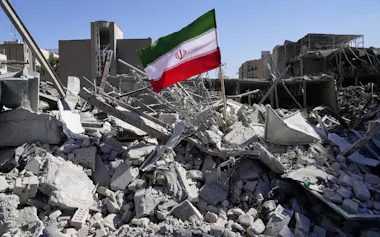 攻撃を受けがれきとなった警察施設に立てられたイラン国旗(3月3日、テヘラン)=AP