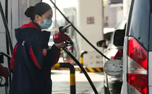 中国のガソリンスタンドで給油をするスタッフ(3月、北京市)=ロイター 中国のガソリンスタンドで給油をするスタッフ(3月、北京市)=ロイター