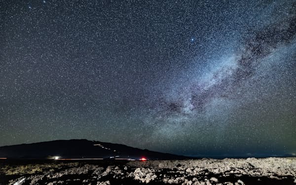 ハワイ島・マウナケア上空の星空。山頂に向かう観光客らの車の光跡が光る