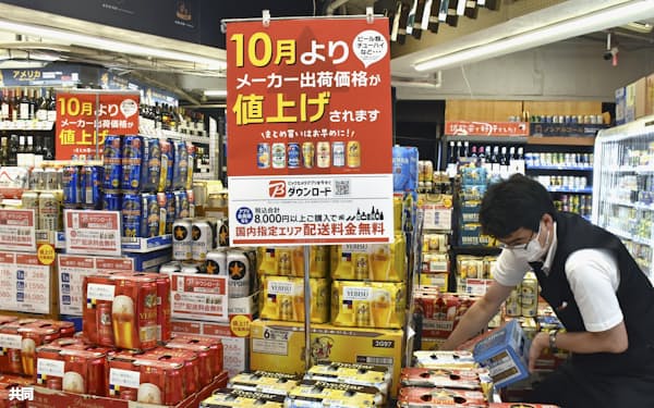 値上げを知らせる紙がアルコール飲料を売るコーナーにかかげられた東京都内の量販店(9月)=共同