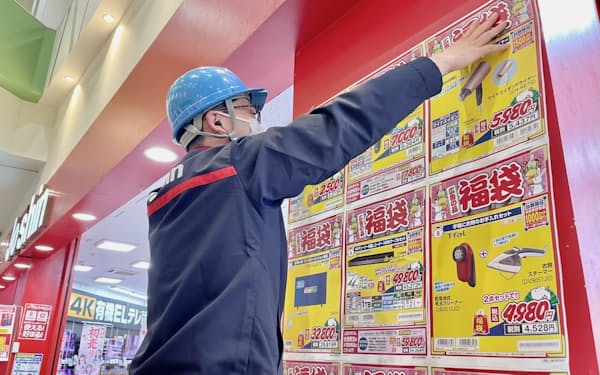 福袋の販促ポスターを貼る上新電機の従業員（23日、大阪府守口市）