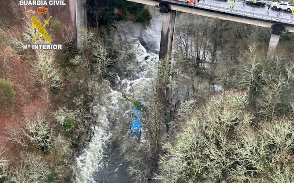 乗用車が橋から川に転落した事故現場で救助活動にあたる救急隊員（25日、スペイン北西部）＝ロイター