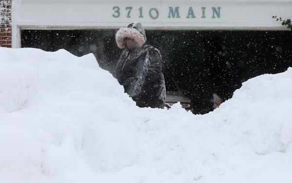 記録的な寒波による降雪で雪かきをする女性（26日、ニューヨーク州バファロー市）＝ロイター