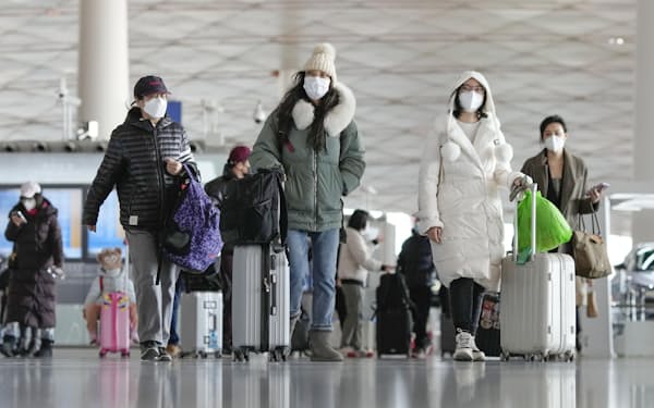 北京首都国際空港の出発ロビーで荷物を引いて歩く人たち（27日）＝共同