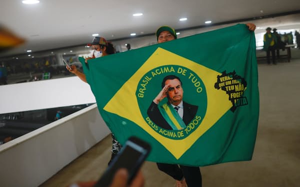 8日、ブラジルのルラ大統領に反対するデモで、ボルソナロ前大統領を描いた旗を掲げる支持者=ロイター