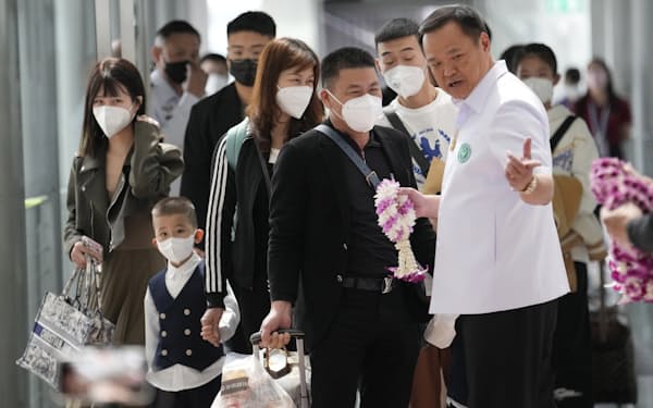 9日、バンコク近郊のスワンナプーム空港で中国人旅行者を出迎えるアヌティン副首相兼保健相㊨＝AP