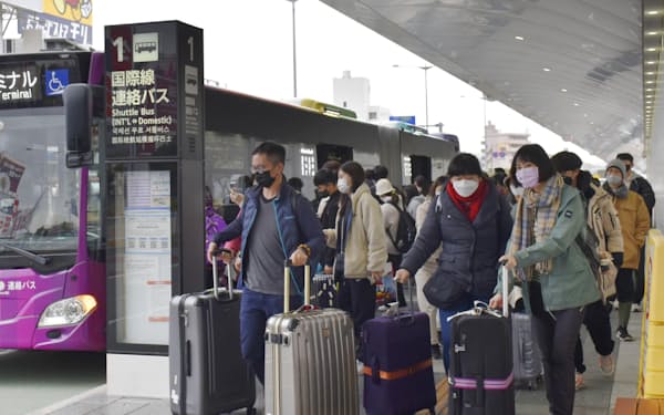 福岡空港で、国際線ターミナルへの連絡バスを利用する外国人旅行客ら（2022年12月13日）＝共同
