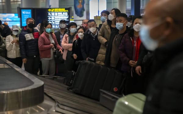 中国の北京首都国際空港で、荷物を待つ旅行者ら（9日）＝AP