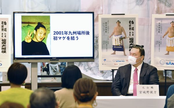 トークイベントに登場した宮城野親方。左の画像は初めてまげを結った当時の写真（11日、東京・両国国技館）＝共同