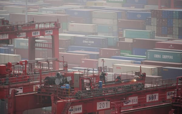 上海の港にあるコンテナと作業員=ロイター・共同
