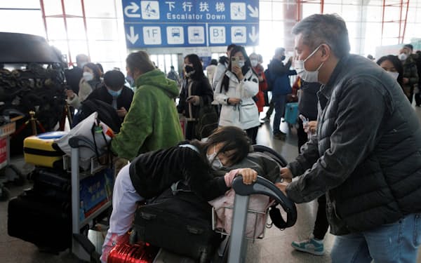 国際旅客便の到着ゲートで荷物を押す乗客たち（８日、北京市の空港）＝ロイター
