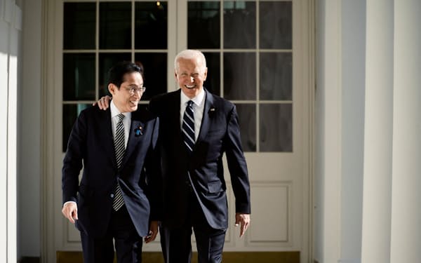 バイデン氏（写真右）と談笑しながら会談会場に向かう岸田文雄首相（13日、ワシントン）＝ロイター