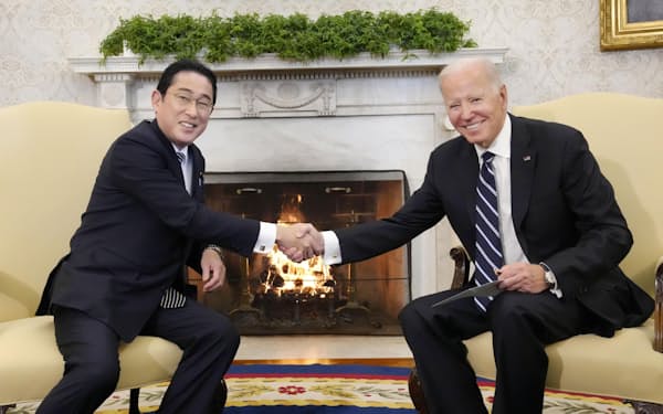 首脳会談を前にバイデン米大統領（右）と握手する岸田首相（13日、ワシントンのホワイトハウス）＝共同