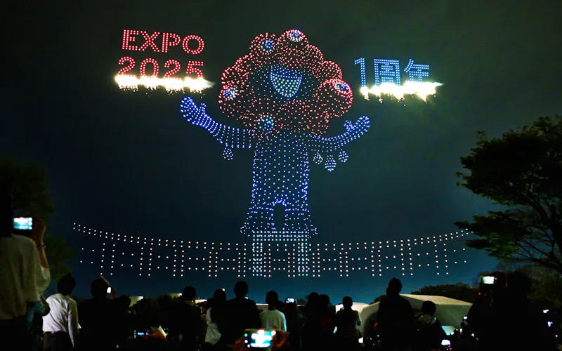 大阪万博の開幕1年を記念したイベントのドローンショーで夜空に浮かび上がる「ミャクミャク」(12日、大阪府吹田市)