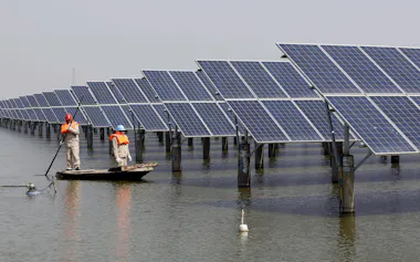 中国江蘇省の池に設置された太陽光パネルを点検する作業員=ロイター