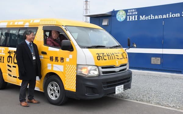 相馬市は23日、IHIの研究拠点でメタン燃料車をお披露目し、立谷秀清市長が試乗した。右奥はメタン製造装置