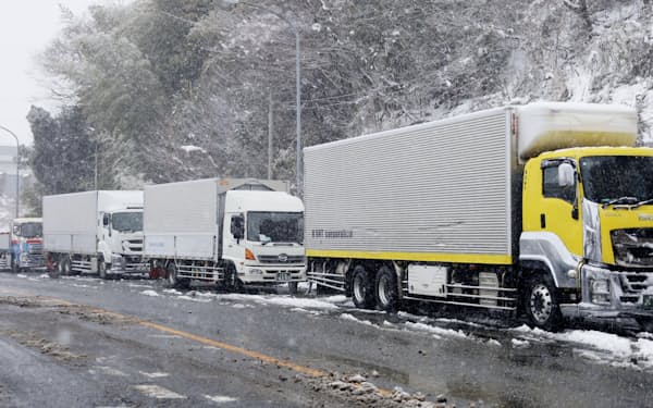 大雪のため東名阪自動車道が通行止めとなり、亀山インターチェンジ付近で待機するトラック（25日、三重県亀山市）＝共同