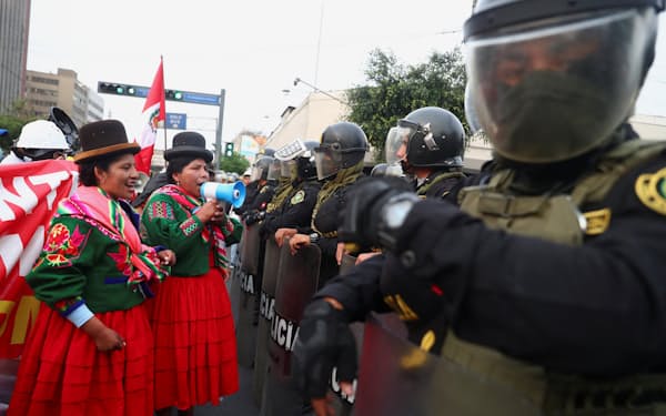 リマでのデモで警官隊と向かい合う民族衣装を着た参加者＝ロイター