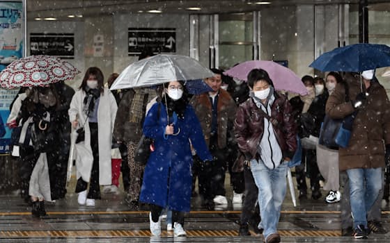 雪が降る中、JR大阪駅前を歩く人たち（27日午前、大阪市北区）