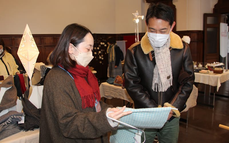 岩手銀の高橋さん㊧は自作のホームスパンを販売している(22年12月、レンガ館) 岩手銀の高橋さん㊧は自作のホームスパンを販売している(22年12月、レンガ館)