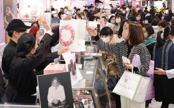 「アムール・デュ・ショコラ」の先行販売会で大きな紙袋で購入した商品を受けとる女性客（18日、JR名古屋高島屋）