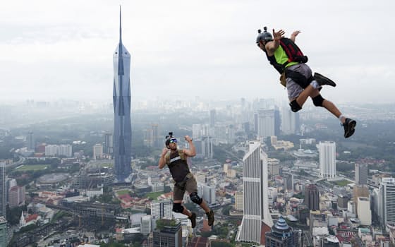 3日にマレーシアのクアラルンプールで開催された、高所から飛び降りてパラシュートで着地する競技「ベースジャンピング」の国際大会で、KLタワー（高さ421メートル）から飛び降りる出場者。かっこいい動画が撮れそうです=AP