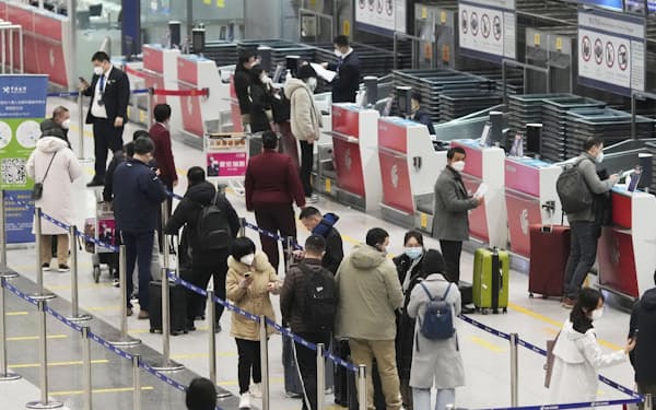 海外への団体旅行が解禁された6日の便の搭乗手続きのため列に並ぶ人たち＝5日夜、北京首都国際空港（共同）