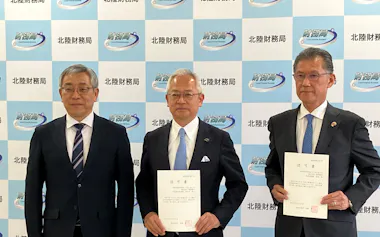 合併認可書を手にする福井銀行の長谷川英一頭取㊥と福邦銀行の湯浅徹頭取㊨(27日、金沢市)