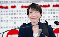 2月8日、衆院選当確者のボードの前で、メディアのインタビューに笑顔で答える自民党総裁の高市首相=東京・永田町の党本部