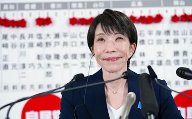 2月8日、衆院選当確者のボードの前で、メディアのインタビューに笑顔で答える自民党総裁の高市首相=東京・永田町の党本部