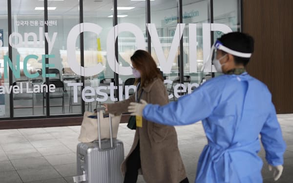 韓国の仁川国際空港に中国から到着し、新型コロナウイルス検査の施設に向かう女性（1月）＝AP・共同