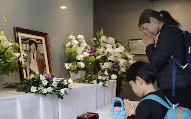 朝日新聞阪神支局に設けられた拝礼所で、小尻知博記者の遺影に向かって手を合わせる人たち(3日、兵庫県西宮市)=共同